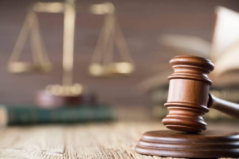 A closeup of a gavel on a car accident attorney 's desk in las vegas. In the background is a blurred-out view of the scales of justice sitting atop a book.