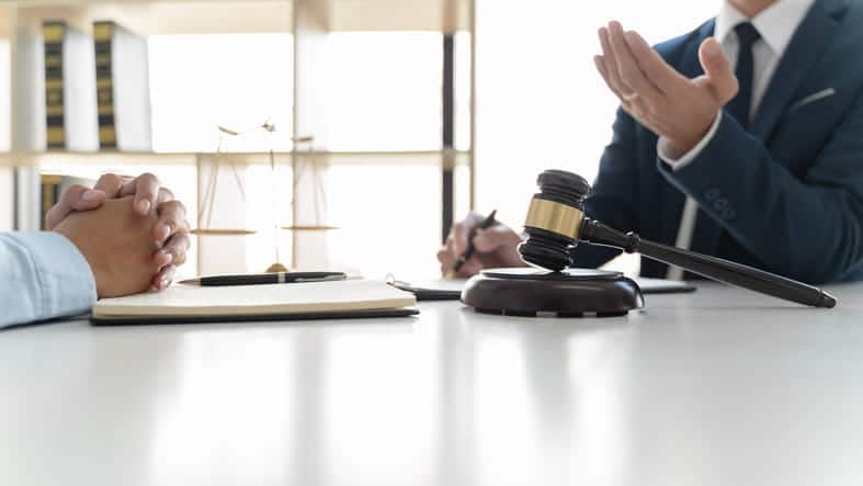 A lawyer discussing a medical malpractice case with a client. Between them is a gavel and paperwork.