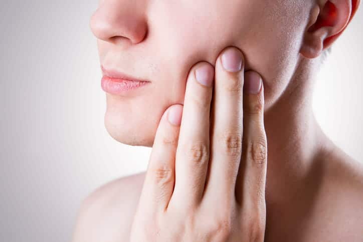 A personal holding their jaw in pain after having a dental accident.