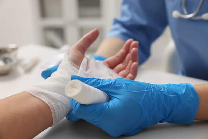 A doctor wrapping a patient's burn injury on their hand with gauze.