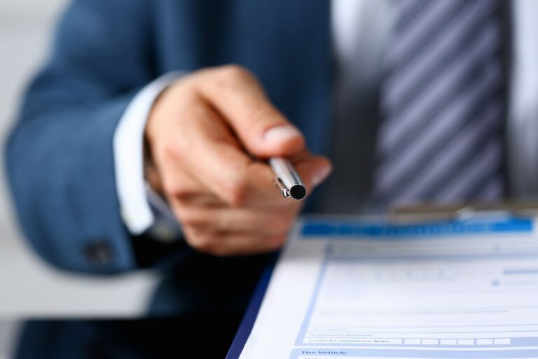 An attorney handing a pen to a client to write down the answers to their car accident questions.