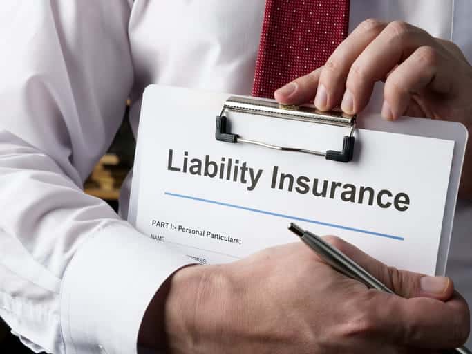 A man holding a clipboard that reads "liability insurance. "